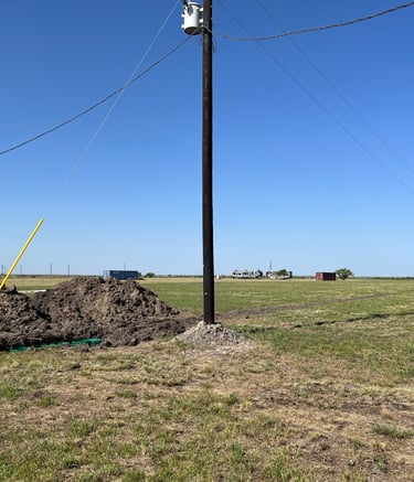 a pile of dirt in a field with a power pole installed nearby
