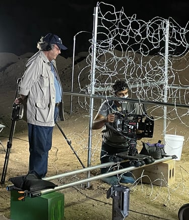 a man wearing a hat and headphones watching a cameraman film on a set