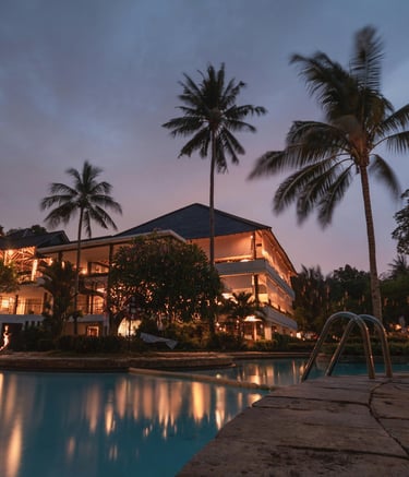 ein Pool und Palmen im Hintergrund ein Hotel