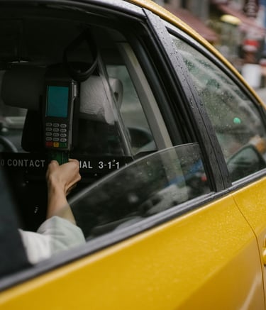 Eine Person fährt in einem Taxi in einer Stadt und bezahlt mit ihrer Kreditkarte