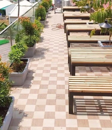 Café landscape with charming seating amidst flowering plants by Garden Designers