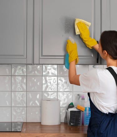 a woman in a white shirt and yellow gloves cleaning a kitchen counter