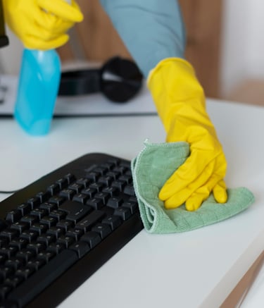 a person cleaning a computer desk with a cloth on it