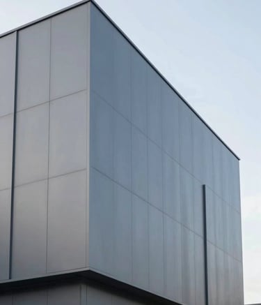 Architectural shot of a modern building facade featuring ACM cladding in a sleek grey finish (#4A5568). The composition is minimalist and low-angle, emphasizing the robustness and clean lines of the aluminum panels against a clear sky.