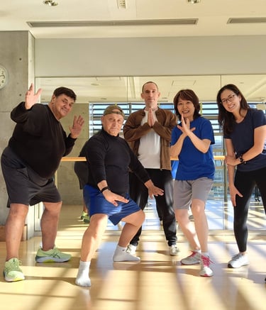 Heng Hu and workshop attendees smiling and posing in a brightly lit fitness studio with wood floors