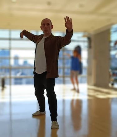 A man practices Tai Chi movements during a martial arts class in a bright fitness studio.