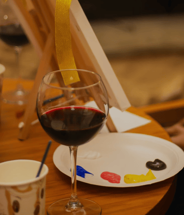 a pant and sip set up with with a glass of wine and paints