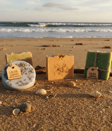 Barras de jabón artesanal hechas a mano con ingredientes naturales exhibidas en una playa arenosa al