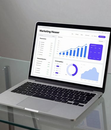 A sleek, modern photography of a laptop on a glass desk displaying a professional marketing analytics dashboard with soft blue and purple data visualizations, minimalist South Asian workspace.