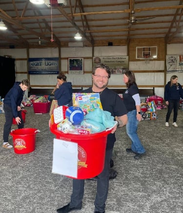 Toy drive at Edge Optics, team member holding bin full of donated toys