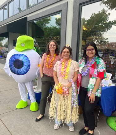 Smiling people with the Edge Optics' eyeball mascot with hula accents