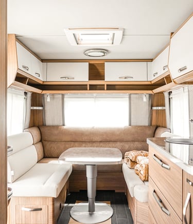 Modern luxury caravan interior with a neutral U-shaped dinette, adjustable table, and wood cabinetry.