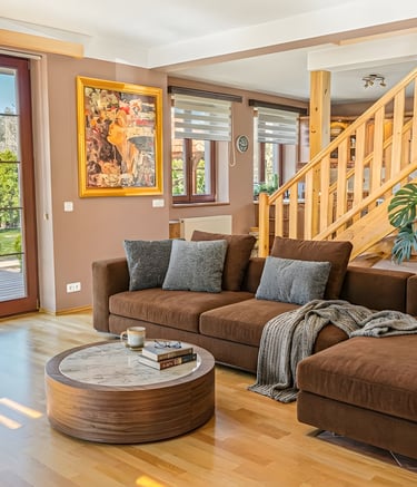 Modern living room with a brown sectional sofa, marble coffee table, and wooden staircase.