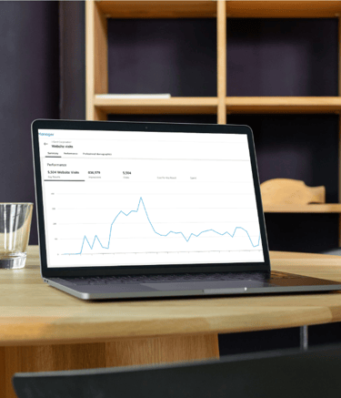 Laptop on a wooden table displaying a business analytics dashboard with website traffic performance charts.