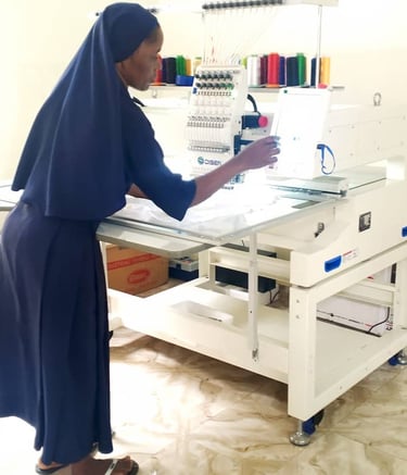 A nun operating a professional computerized industrial embroidery machine in a garment workshop.