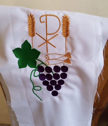 Embroidered white altar cloth featuring Chi Rho symbol, golden wheat stalks, and purple grapes.