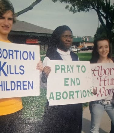 Three pro-life demonstrators including a nun holding anti-abortion signs at a public protest.