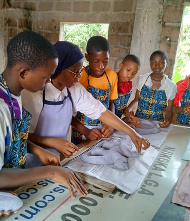 Students in a workshop learning clay modeling and sculpture techniques with a teacher.