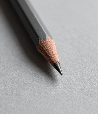 A close-up, high-detail shot of a sharp graphite pencil tip against a textured light gray paper #D9D9D9. Minimalist composition with a focus on precision and sharp edges. Dramatic soft lighting from the side creating subtle shadows in #333333.