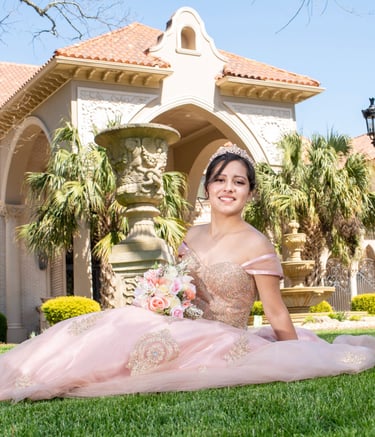 Elegant Quinceañera in a pink dress sitting on the grass