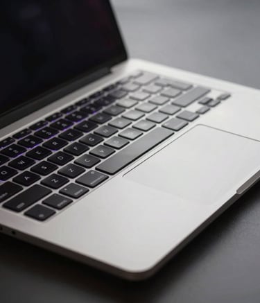 A close-up of a high-end metal laptop keyboard with subtle purple backlighting in a dark, minimalist room, professional and modern, North American / International.