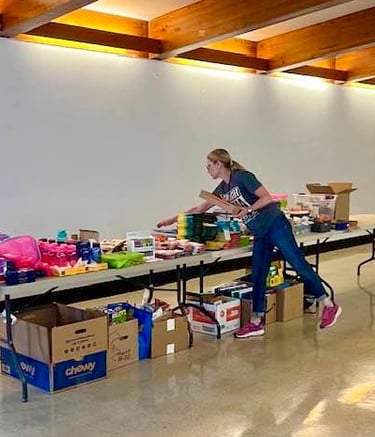 Volunteer woman arranging school supplies on table