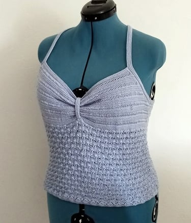 Top d'été tricoté avec un fil coton bleu clair il est posé sur un mannequin de couturière 