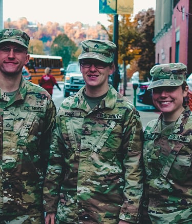 Male and female military in camoflage uniforms standing together in a town plaza