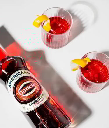 Un bouteille d'aperitivo et deux verres de spritz sur une table blanche
