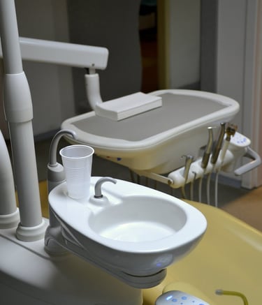Professional dental chair station with a white rinsing sink and plastic water cup.
