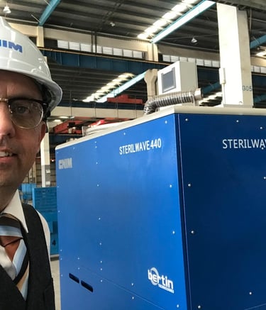 Engineer in a hard hat standing by a Bertin Sterilwave 440 medical waste treatment machine.