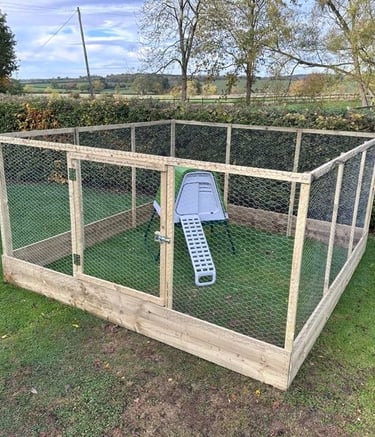 Large wooden chicken run with wire mesh and a small coop on a green lawn.