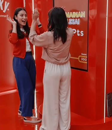Two female participants high-fiving and laughing after playing at Pocky booth