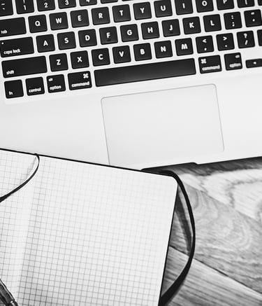 a laptop, notebook, pen and a cup of coffee