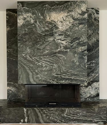 Luxury fireplace feature wall with dramatic dark green and grey bookmatched marble slabs.