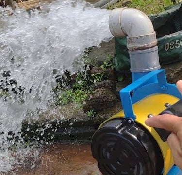 A portable electric water pump machine discharging a high-pressure stream for agricultural irrigation.