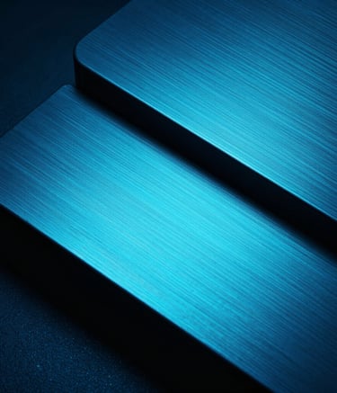 Macro photography of a sleek, brushed metal surface reflecting electric cyan light in a dark blue environment. The composition is abstract and futuristic, emphasizing high-end hardware and advanced technology with deep black shadows. Professional architectural photography style.