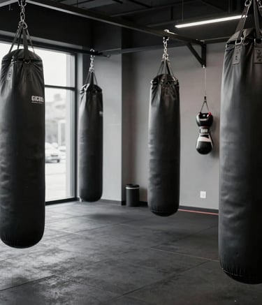 Interior of a modern, high-end boxing and conditioning gym with heavy bags and professional gear. Focus on the clean, masculine aesthetic of the space. Deep Black and Slate Gray color palette. Global / Performance Athletics.