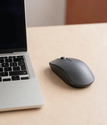 Macro photography of a sleek laptop keyboard and a high-precision mouse on a soft sand-colored desk. The scene is shot in a bright South American office setting with natural lighting and soft terracotta accents in the background. No people are in the frame.