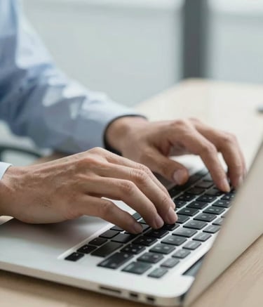 A close-up of professional hands typing on a modern laptop keyboard in a bright South American / Brazilian corporate setting, soft light blue and pale off-white tones, clean and professional lighting.