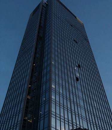A low-angle shot of a modern glass skyscraper reflecting a deep midnight blue sky. The architecture is clean and sharp, representing the corporate authority and sophisticated modern legal environment of the firm.