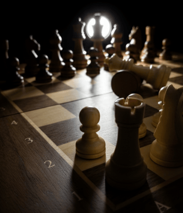 Dramatic wooden chessboard setup with a glowing white light highlighting the king and rook pieces.