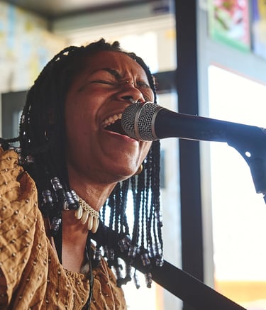 una mujer afro cantando con un micrófono