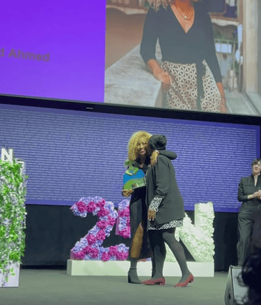 Dos mujeres afro abrazandose una de ellas sujetando un premio