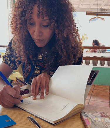 una mujer afro escribiendo en un libro