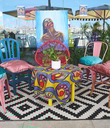 Una mesa colorida con sillas y una mesa con una planta en maceta.