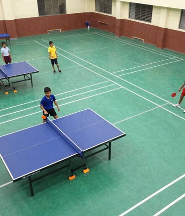An expansive sports field with students playing cricket under clear skies.