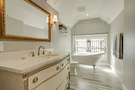 Luxury master bathroom featuring a white clawfoot tub and vintage vanity with marble countertop.