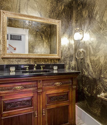 Luxury powder room with wooden vanity, and ornate mirror.