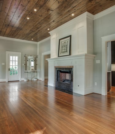 Modern living room featuring a white fireplace mantel, wood plank ceiling, and polished hardwood floors.